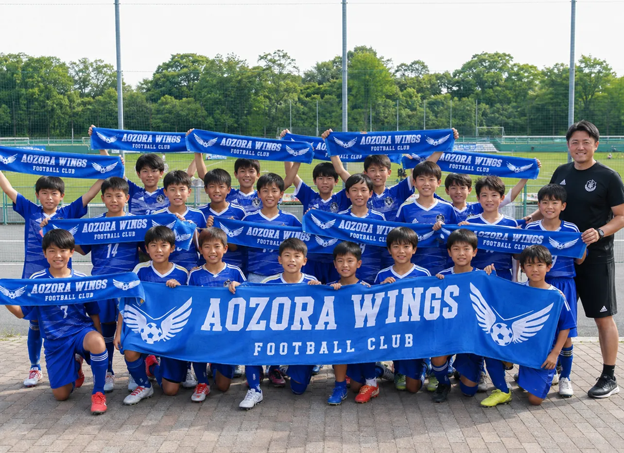 お揃いのタオルを掲げるサッカーチーム